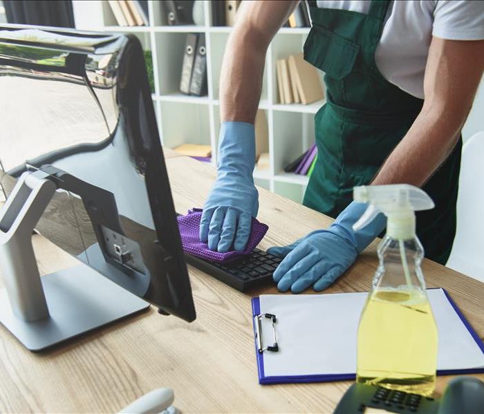 Cropped shot of professional cleaner in rubber gloves cleaning computer keyboard in office